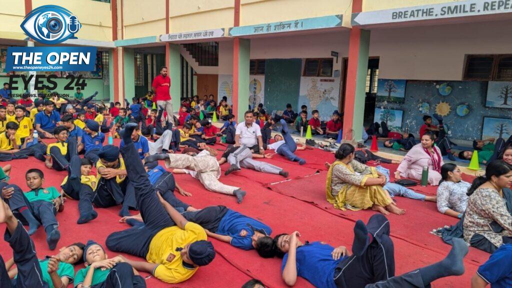 ਬਰਨਾਲਾ ਦੇ ਵਾਯੂ ਸੈਨਾ ਸਥਾਨ ਸਥਿਤ ਕੇਂਦਰੀ ਵਿਦਿਆਲਿਆ ਵਿਖੇ ਅੰਤਰਰਾਸ਼ਟਰੀ ਯੋਗ ਦਿਵਸ ਮੌਕੇ ਸਮੂਹਿਕ ਯੋਗ ਆਸਨ ਕਰਦੇ ਹੋਏ ਬੱਚੇ, ਅਧਿਆਪਕ ਅਤੇ ਮੰਚ ਤੋਂ ਯੋਗ ਸਾਧਕਾਂ ਨੂੰ ਸਨਮਾਨਿਤ ਕੀਤੇ ਜਾਣ ਦਾ ਦ੍ਰਿਸ਼।